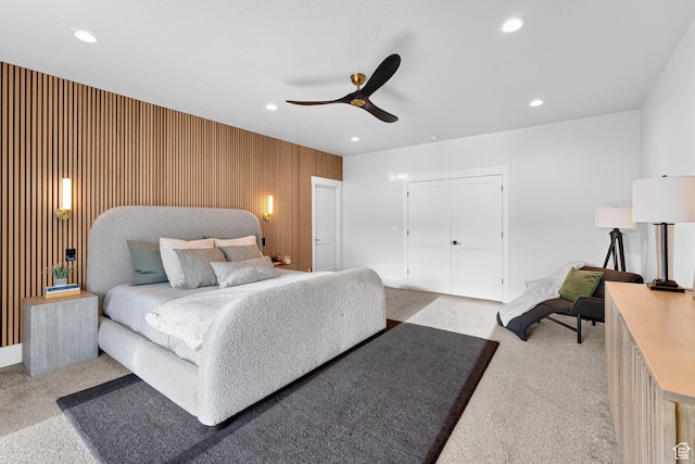 bedroom with light colored carpet, wooden walls, recessed lighting, and a ceiling fan