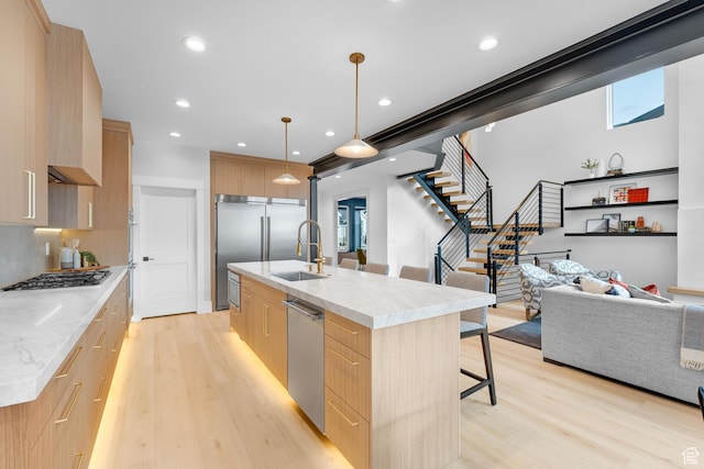 kitchen featuring light brown cabinets, modern cabinets, a sink, and light wood-style floors