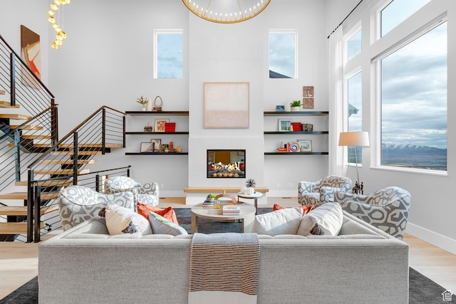 living room featuring baseboards, a high ceiling, wood finished floors, and stairway