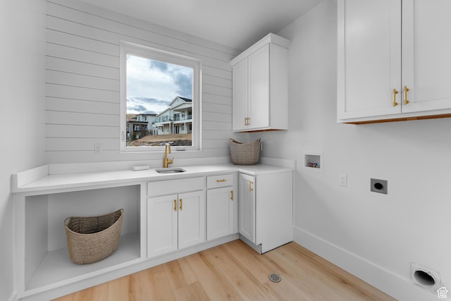 laundry area featuring a sink, light wood finished floors, washer hookup, hookup for an electric dryer, and cabinet space