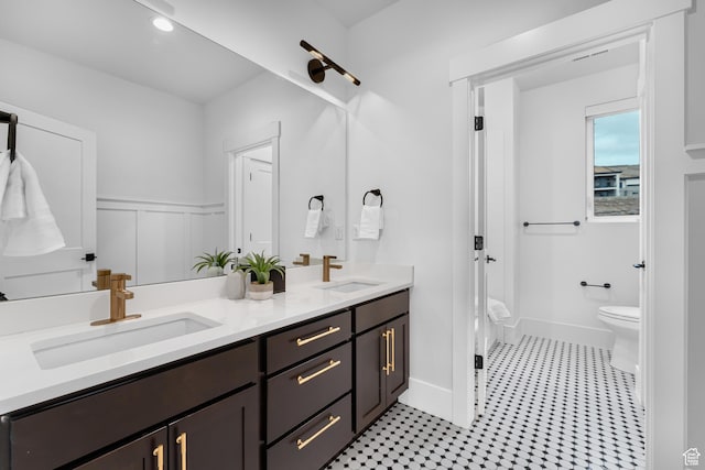 full bath featuring double vanity, toilet, a sink, and walk in shower
