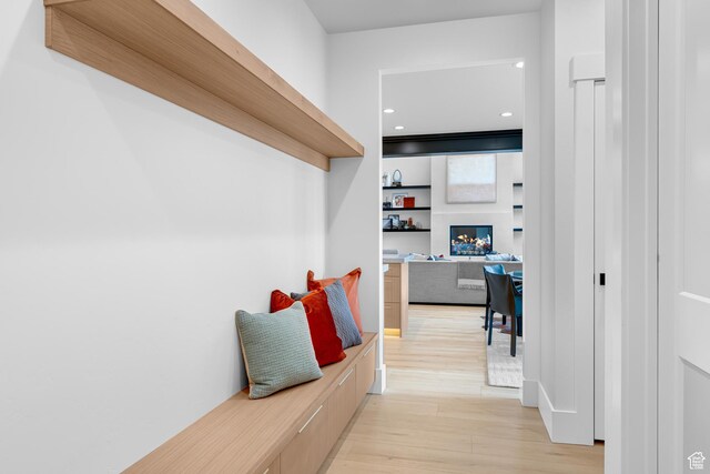 mudroom featuring a lit fireplace, light wood finished floors, and recessed lighting