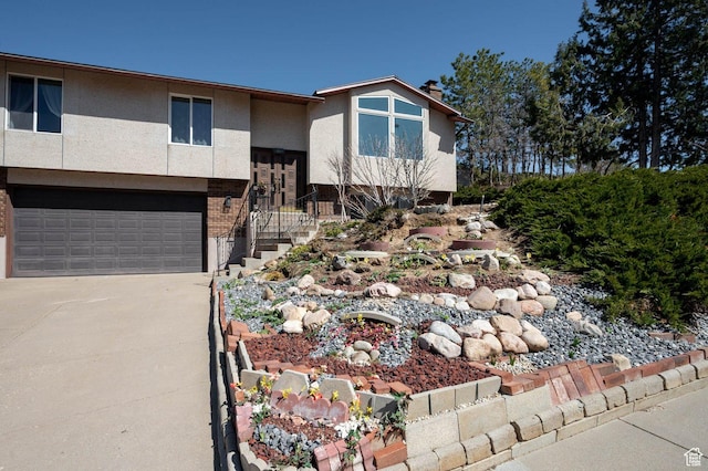 view of front of house with driveway, a chimney, a garage, and stucco siding