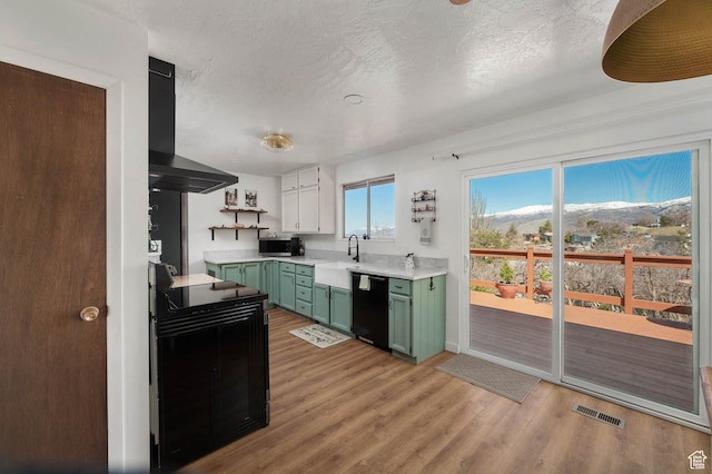 761 E Raygene Way S, North Salt Lake, UT 84054 - kitchen with green cabinets, light countertops, visible vents, black appliances, and wall chimney exhaust hood