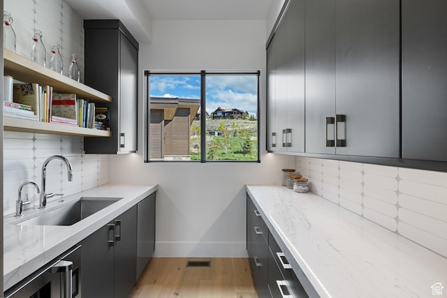 7045 E Moon Light Dr, Heber City, UT 84032 - kitchen with a sink, light wood-type flooring, backsplash, baseboards, and light stone countertops