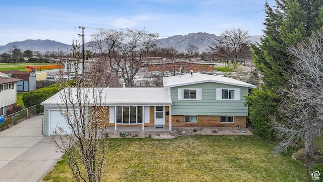 split level home featuring a front yard, a garage, a mountain view, and concrete driveway