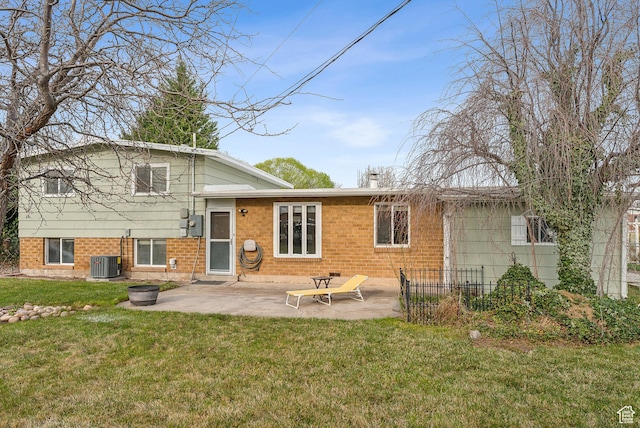 rear view of property featuring brick siding, central air condition unit, a yard, and a patio area