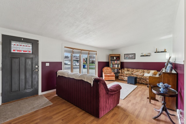 living room with a wainscoted wall, a textured ceiling, and wood finished floors