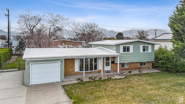 tri-level home featuring driveway, a front yard, fence, an attached garage, and a porch