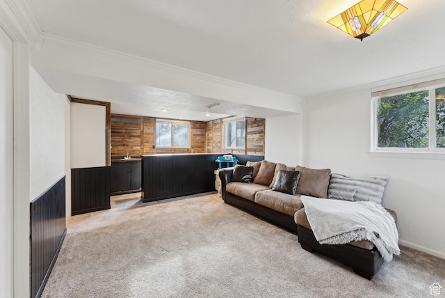 living area featuring crown molding, light colored carpet, wooden walls, and baseboards