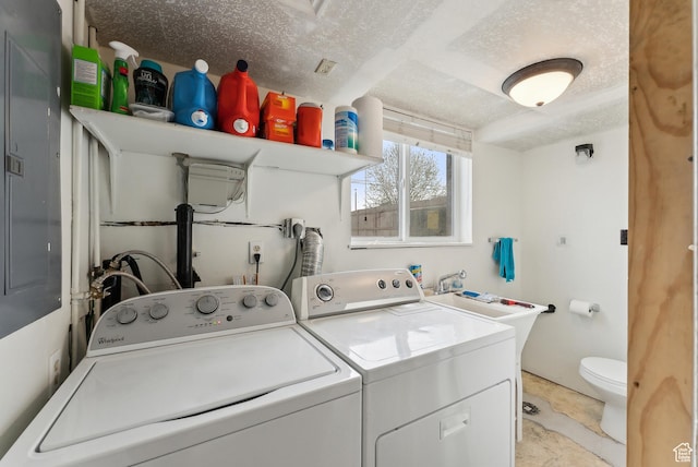 clothes washing area with washing machine and dryer, a textured ceiling, and laundry area