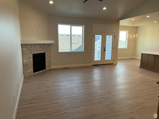 unfurnished living room featuring a fireplace, recessed lighting, light wood-style floors, and ceiling fan with notable chandelier