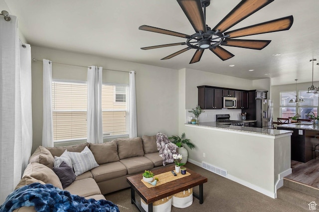 living room featuring baseboards, visible vents, dark colored carpet, and ceiling fan
