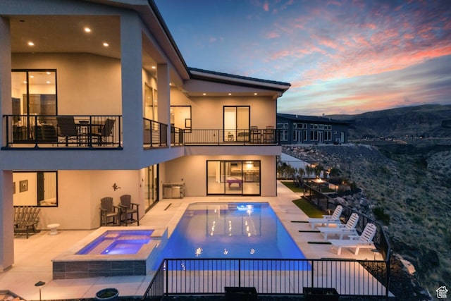 599 W 170 S, La Verkin, UT 84745 - back of house at dusk with a balcony, a pool with connected hot tub, stucco siding, and a patio