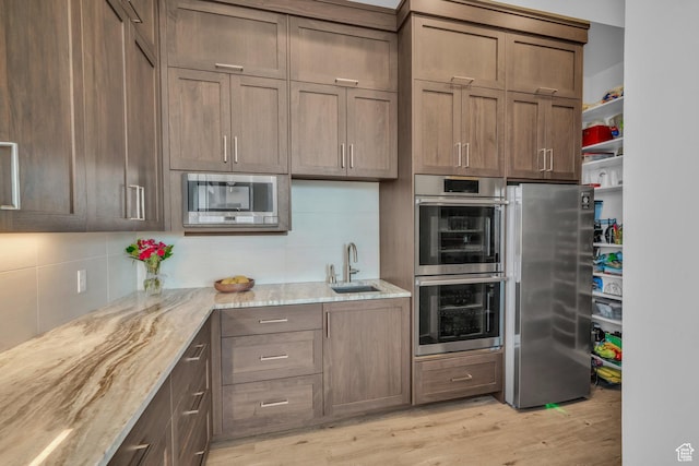 599 W 170 S, La Verkin, UT 84745 - kitchen with decorative backsplash, a sink, light wood-style floors, light stone countertops, and appliances with stainless steel finishes