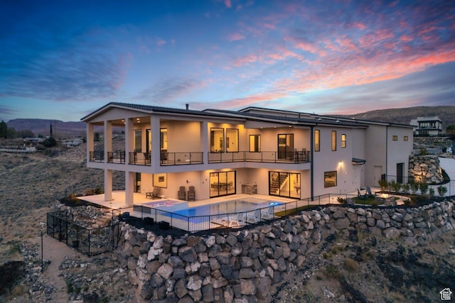 599 W 170 S, La Verkin, UT 84745 - back of house at dusk featuring stucco siding, fence, stairs, a balcony, and a patio area