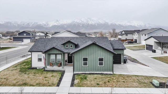 602 W 20 N, Hyrum, UT 84319 - view of front of house featuring a front yard, concrete driveway, board and batten siding, a shingled roof, and a mountain view