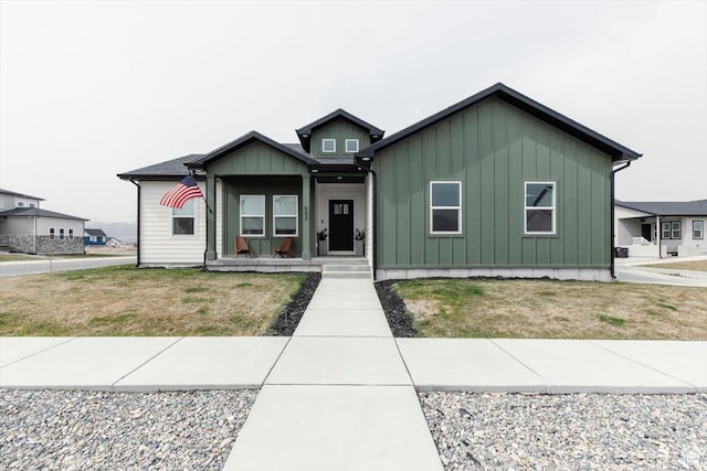 view of front of house featuring a front lawn, covered porch, and board and batten siding
