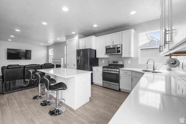 13099 S Twisted Oak Dr, Herriman, UT 84096 - kitchen featuring a sink, a kitchen island, a breakfast bar area, wood finished floors, and stainless steel appliances