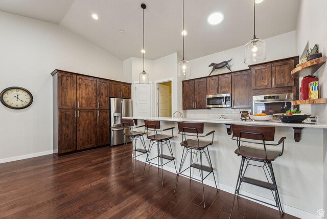 5265 N Laurelwood St N, Heber City, UT 84032 - kitchen featuring a kitchen bar, dark brown cabinets, vaulted ceiling, and stainless steel appliances