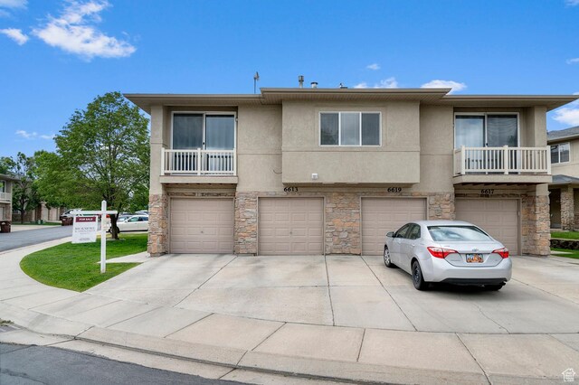 6613 W Ivy Gable Dr, West Jordan, UT 84081 - townhome / multi-family property with stone siding, a garage, stucco siding, and driveway