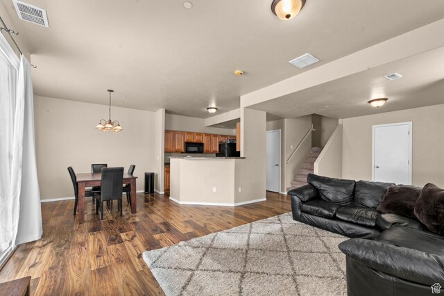 6613 W Ivy Gable Dr, West Jordan, UT 84081 - living room featuring dark wood-style flooring, stairway, a chandelier, and baseboards