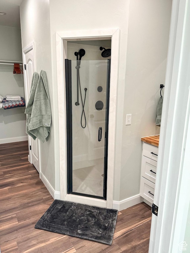 690 N Main St, Antimony, UT 84712 - bathroom featuring baseboards, wood finished floors, a stall shower, and vanity