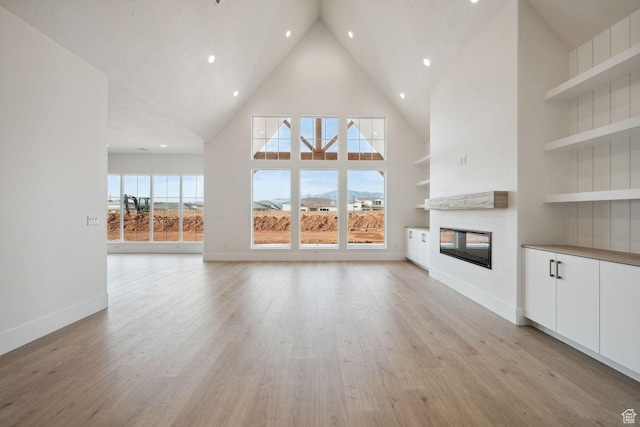 3087 E 2220 S, St George, UT 84790 - unfurnished living room with a multi sided fireplace, high vaulted ceiling, recessed lighting, built in shelves, and light wood-type flooring