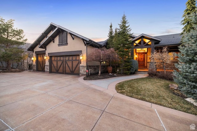 view of front of property featuring stone siding, concrete driveway, and stucco siding
