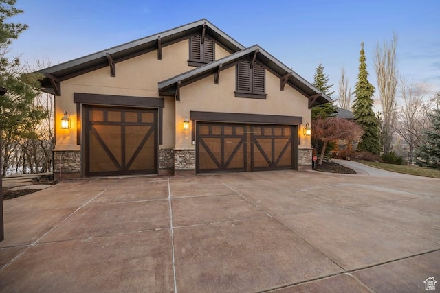 view of front of property featuring stone siding, concrete driveway, stucco siding, and an attached garage