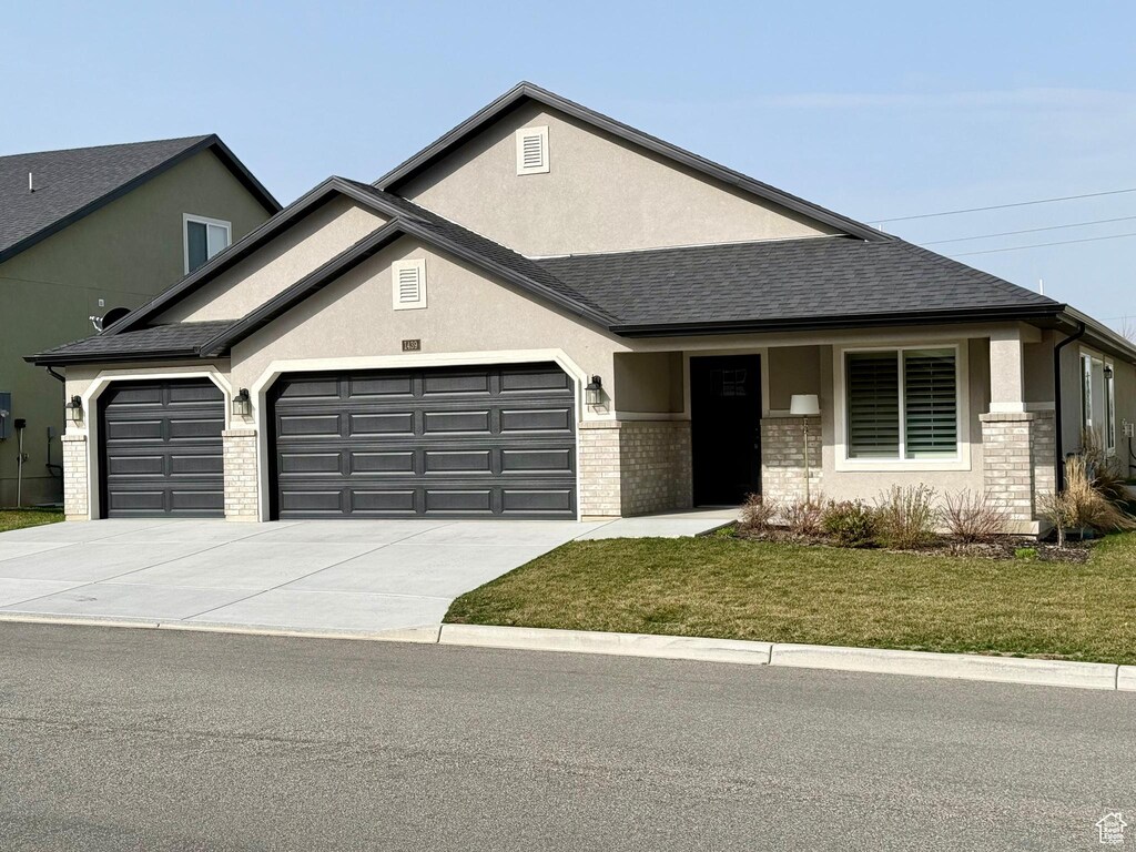 view of front of home with driveway, a garage, a front lawn, stucco siding, and a shingled roof