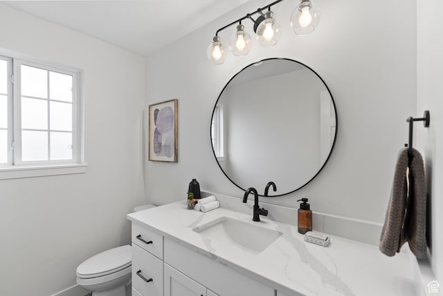 bathroom featuring toilet, baseboards, and vanity