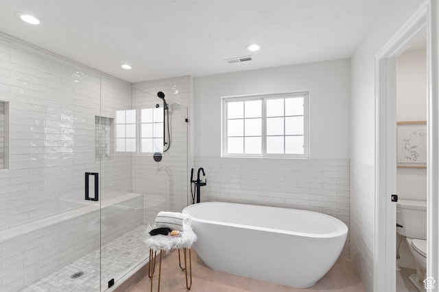 bathroom featuring a stall shower, a freestanding bath, toilet, and visible vents