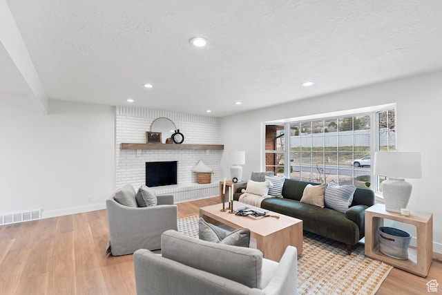 living area with baseboards, light wood-style flooring, a fireplace, and recessed lighting