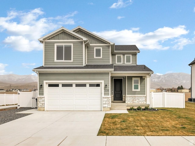 craftsman inspired home with board and batten siding, concrete driveway, a mountain view, and fence