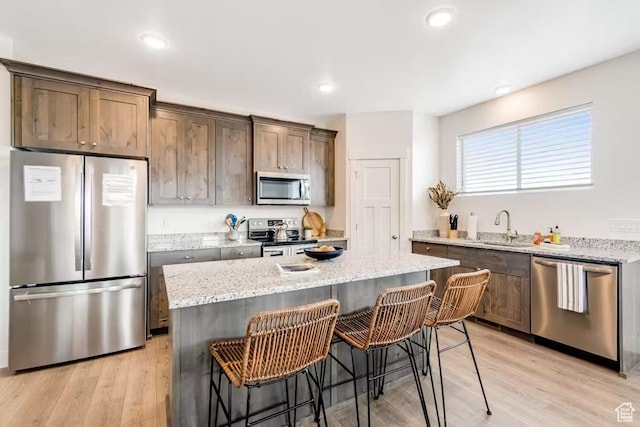 2233 S Beachcomber Ln, Garden City, UT 84028 - kitchen with light stone counters, a sink, a breakfast bar, stainless steel appliances, and light wood-style floors