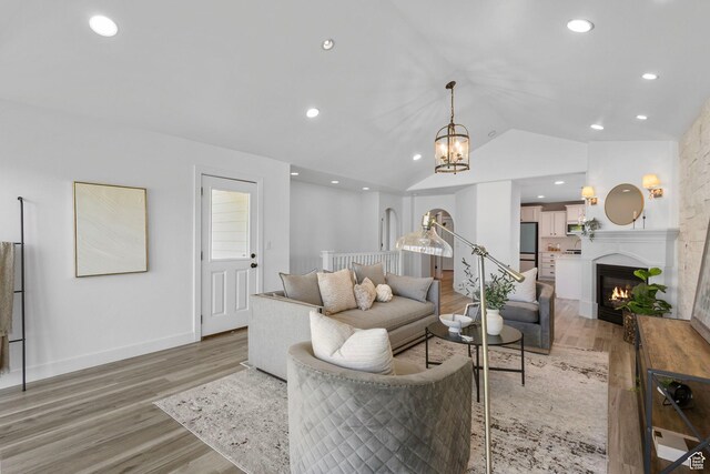 5025 N Shady Bend Ln, Lehi, UT 84043 - living room with a warm lit fireplace, light wood-style floors, vaulted ceiling, a chandelier, and recessed lighting