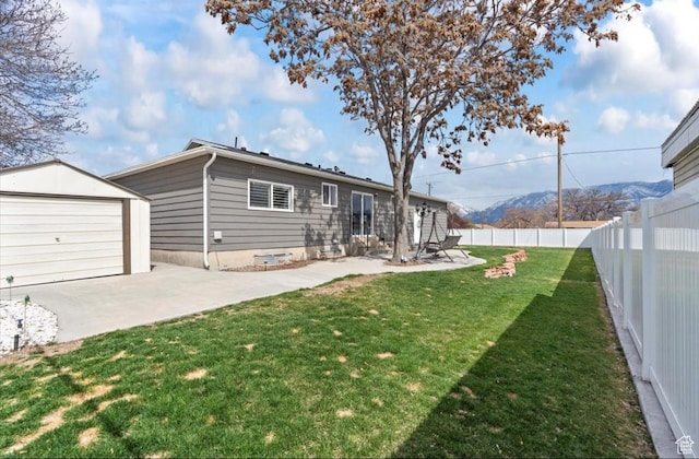 exterior space with an outdoor structure, a fenced backyard, a mountain view, a patio area, and a lawn