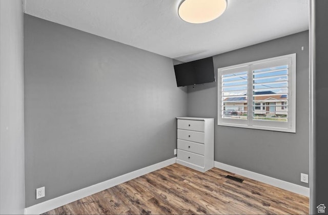 empty room featuring visible vents, baseboards, and wood finished floors