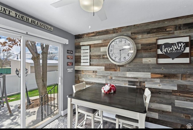 dining area featuring wooden walls and a ceiling fan