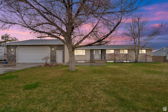 ranch-style house featuring a lawn, an attached garage, concrete driveway, and brick siding