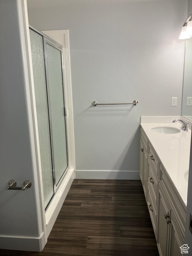 285 W 1580 N Unit 102, Logan, UT 84341 - bathroom featuring a shower stall, baseboards, double vanity, wood finished floors, and a sink