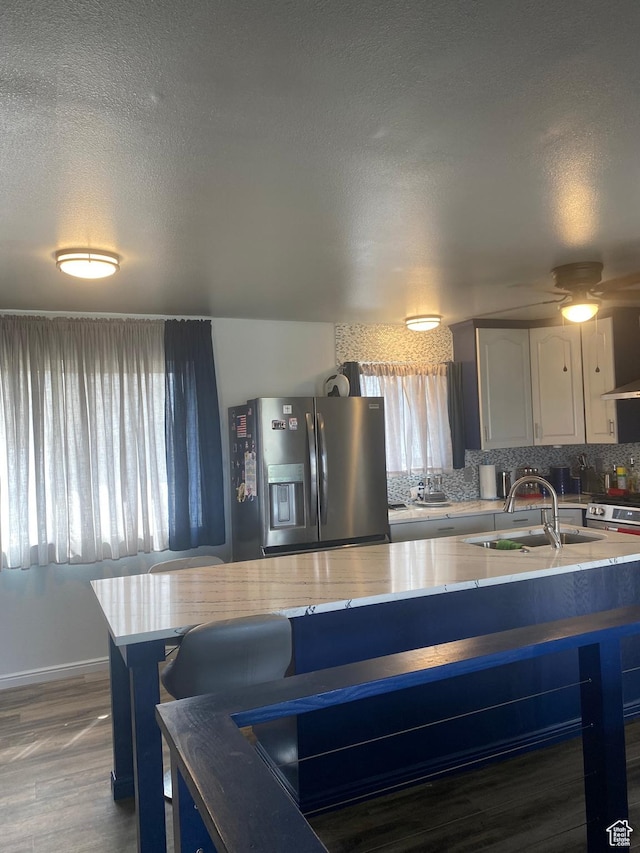 6489 W Castle View Dr S, West Valley City, UT 84128 - kitchen featuring light stone counters, a sink, tasteful backsplash, appliances with stainless steel finishes, and a textured ceiling