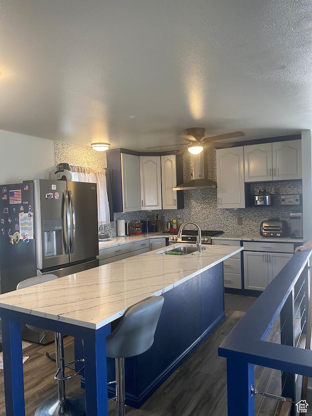 6489 W Castle View Dr S, West Valley City, UT 84128 - kitchen with stainless steel fridge with ice dispenser, decorative backsplash, wall chimney range hood, and dark wood finished floors