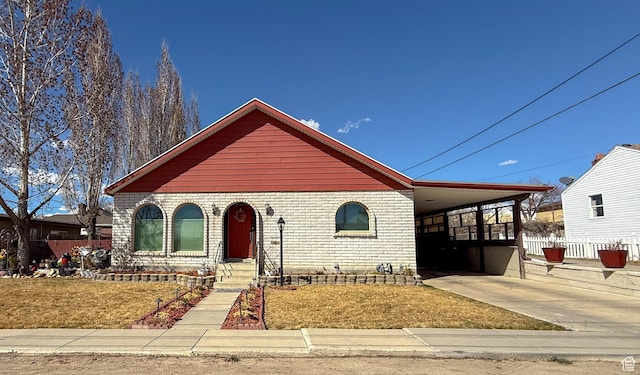 view of front of property featuring brick siding, an attached carport, concrete driveway, and fence