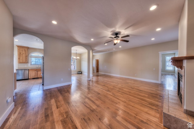 494 E Kachina Way, Moab, UT 84532 - unfurnished living room with recessed lighting, ceiling fan with notable chandelier, arched walkways, light wood-style flooring, and a glass covered fireplace