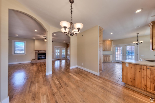 494 E Kachina Way, Moab, UT 84532 - kitchen featuring ceiling fan with notable chandelier, a fireplace, light wood-type flooring, and french doors