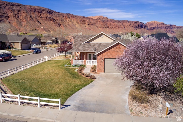 494 E Kachina Way, Moab, UT 84532 - ranch-style home featuring driveway, fence, brick siding, a front lawn, and a mountain view