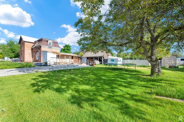 477 N 300 W, Brigham City, UT 84302 - view of yard with fence, a garage, a storage unit, driveway, and an outdoor structure