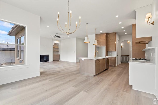 1065 W 125 S, Lehi, UT 84043 - kitchen with arched walkways, a sink, brown cabinetry, light countertops, and an island with sink
